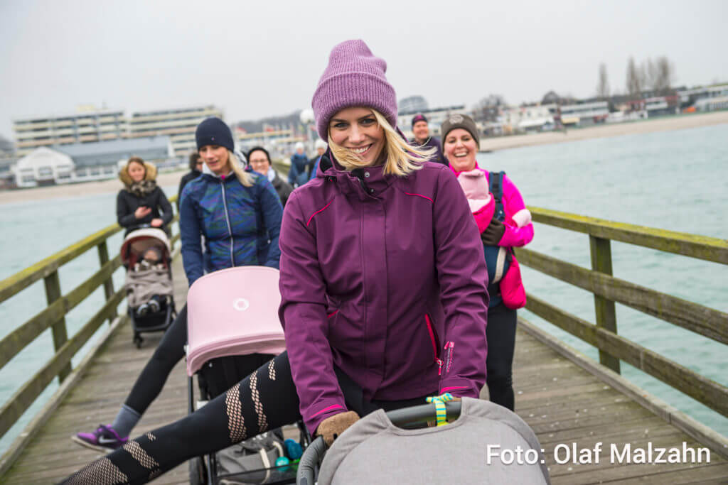 Mamas in einer Gruppe mit Baby machen Sport. Mit Kinderwagen und Babytrage.