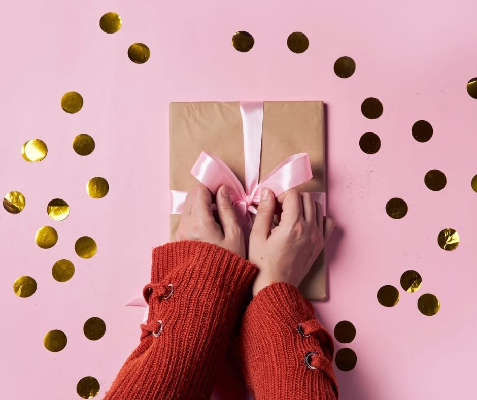 Geschenk mit rosa Schleife, das gerade geöffnet wird.